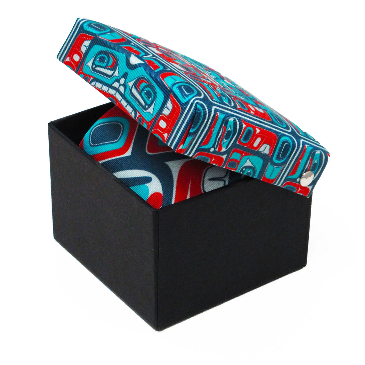A black presentation box with a lid featuring a bold red, blue, and white geometric totem-style pattern, shown open on a white background.