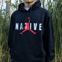 Person wearing a black hoodie with a red and white logo in a natural setting