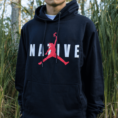 Person wearing a black hoodie with a red and white logo in a natural setting