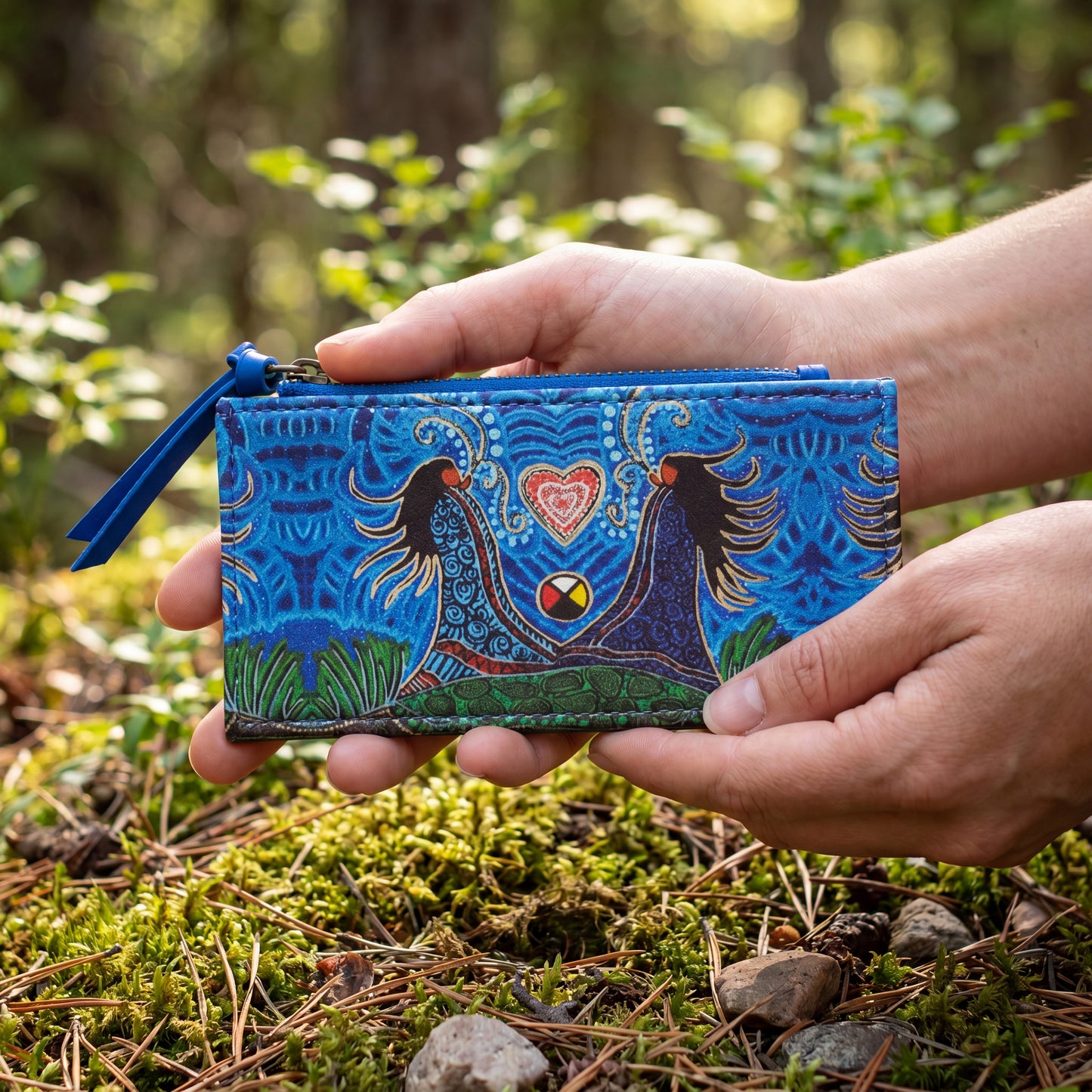 Hand holding a blue patterned pouch in a forest setting