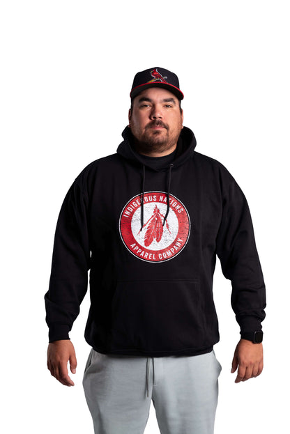 Man wearing a black hoodie with a red logo and a cap on a white background