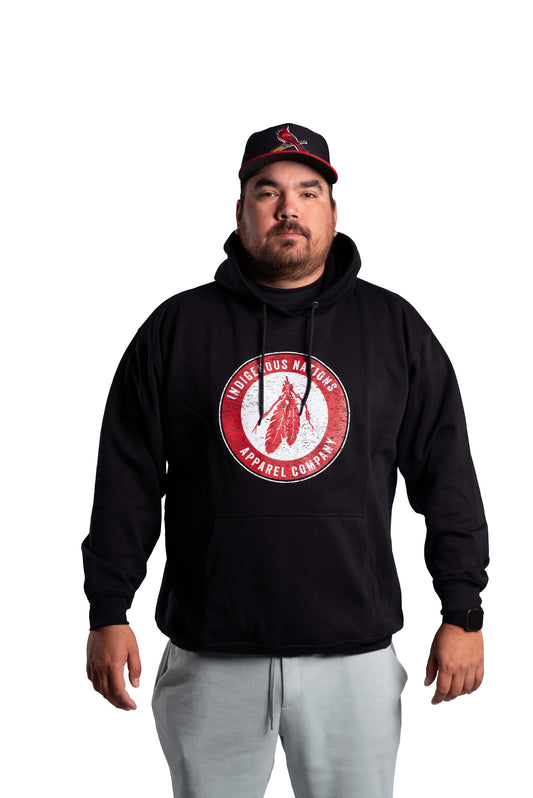 Man wearing a black hoodie with a red logo and a cap on a white background