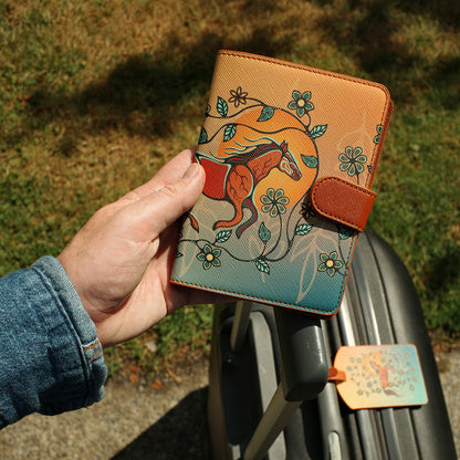 Hand holding a leather wallet with horse design against a blurred outdoor background