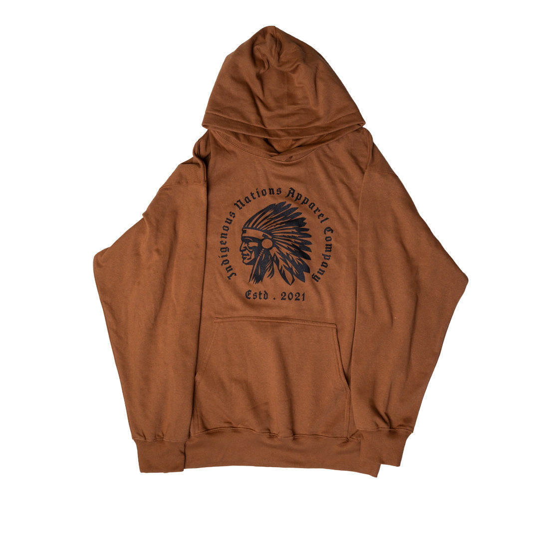 A brown pullover hoodie with a black circular graphic on the chest featuring a Native American headdress and the text 'Indigenous Nations Apparel Company' and 'Estd. 2021'.