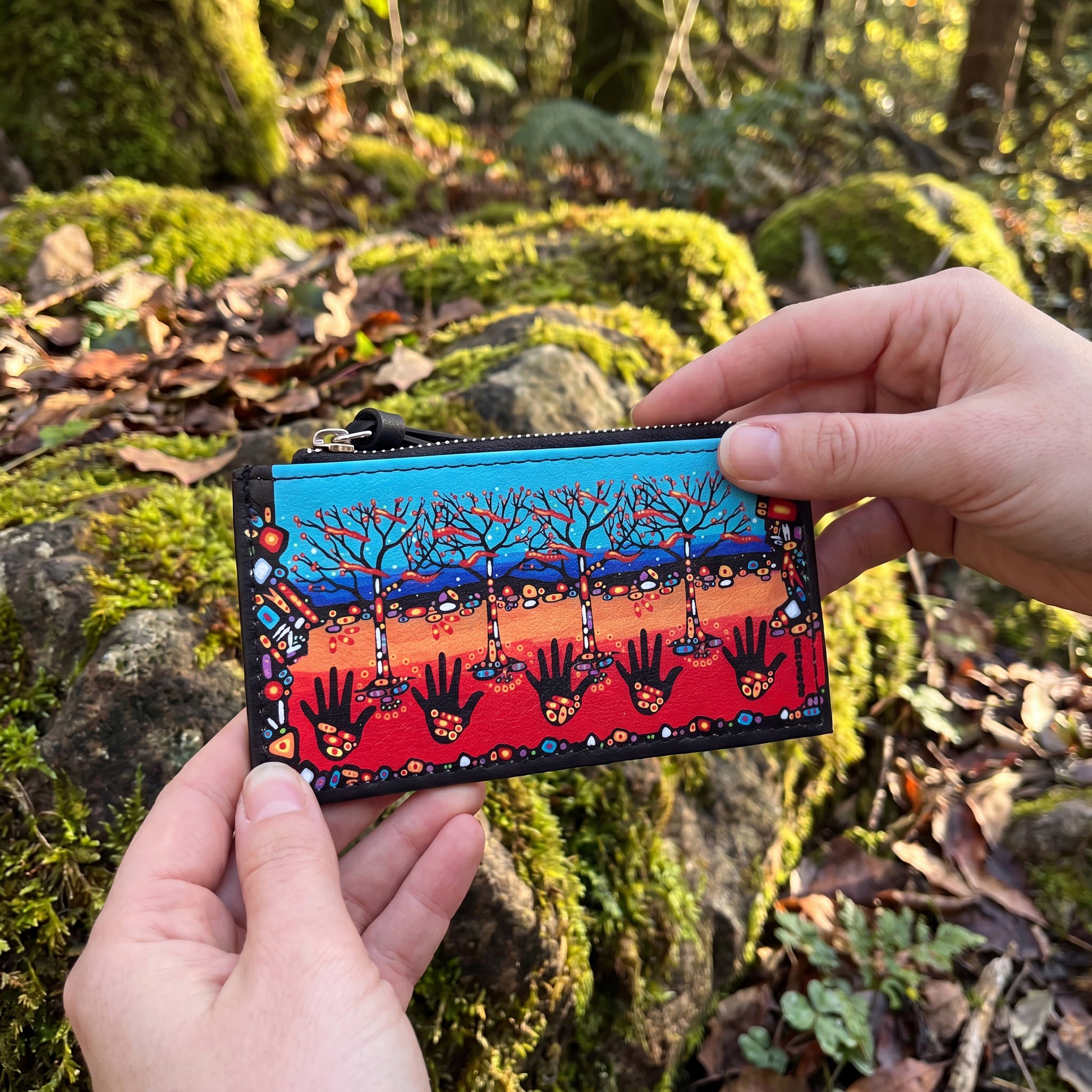 Colorful wallet with artistic design held by hands against a natural background