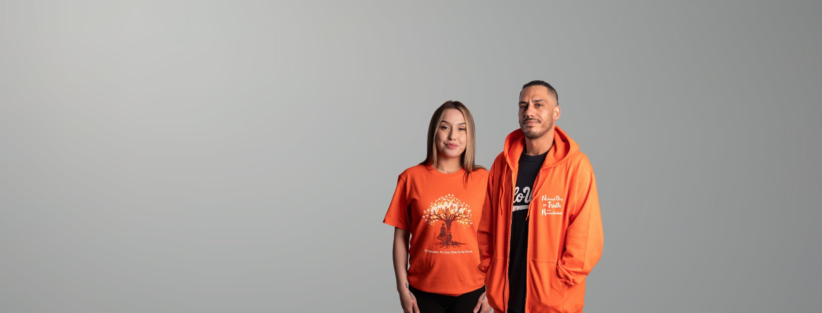 Two people wearing orange hoodies with logos on a gray background
