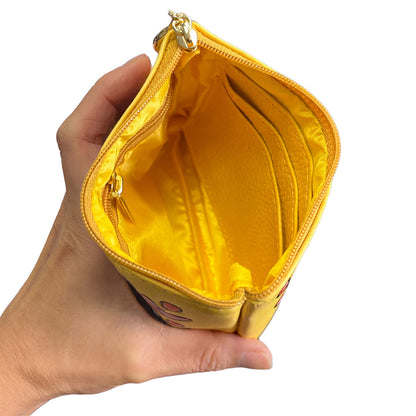 Hand holding a yellow pouch with a white background