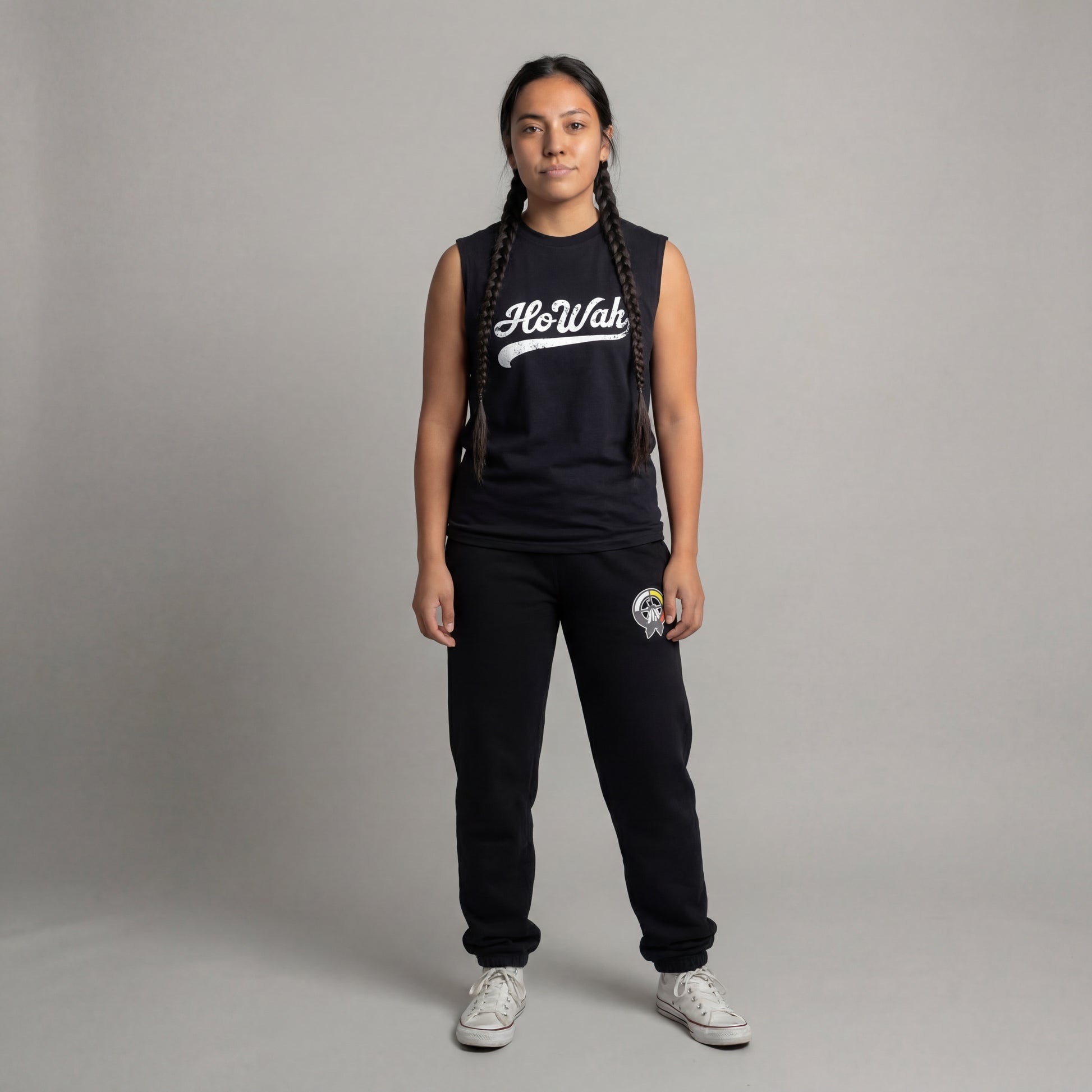 Person wearing a black sleeveless shirt with 'HoWah' text and black pants on a gray background