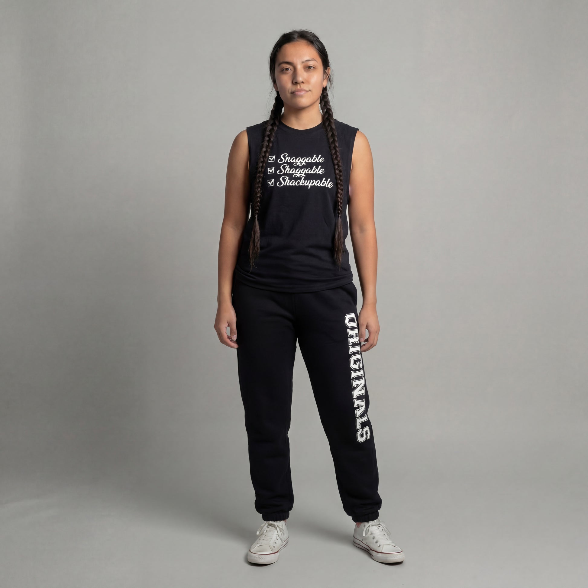 Person wearing a black sleeveless top and black pants with 'originals' text, standing against a gray background.