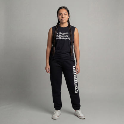 Person wearing a black sleeveless top and black pants with 'originals' text, standing against a gray background.