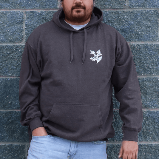 Person wearing Cedar Medicine Hoodie in black with cedar leaf chest design