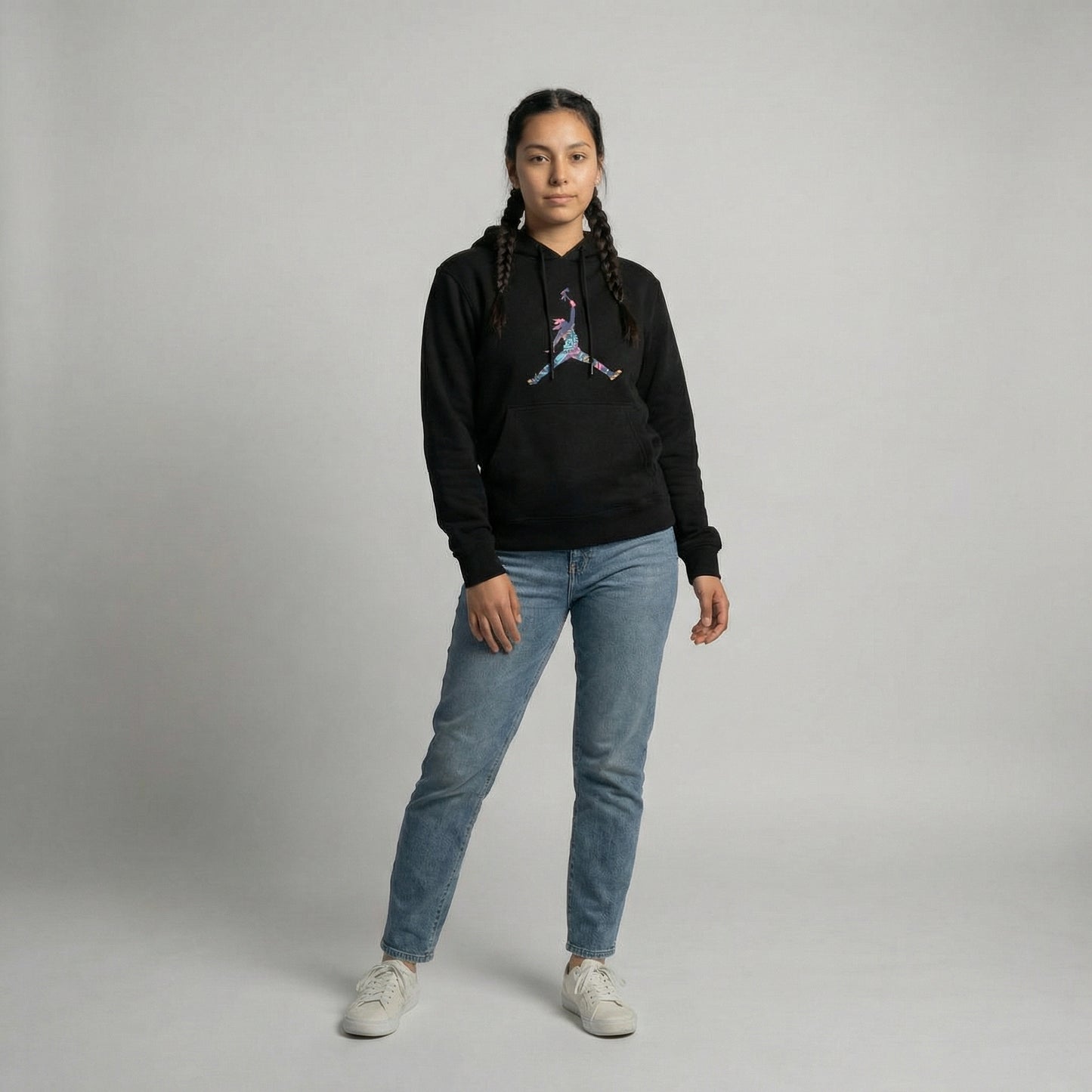 Model wearing Tribal Leap Hoodie in black with colorful graphic, paired with light blue jeans.