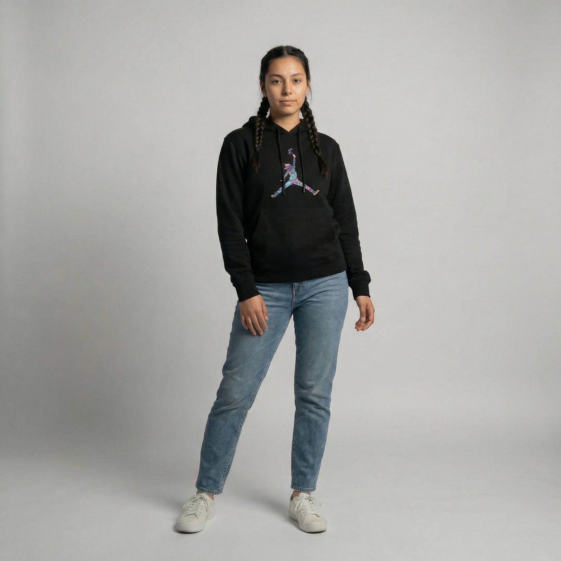 Model wearing Tribal Leap Hoodie in black with colorful graphic, paired with light blue jeans.