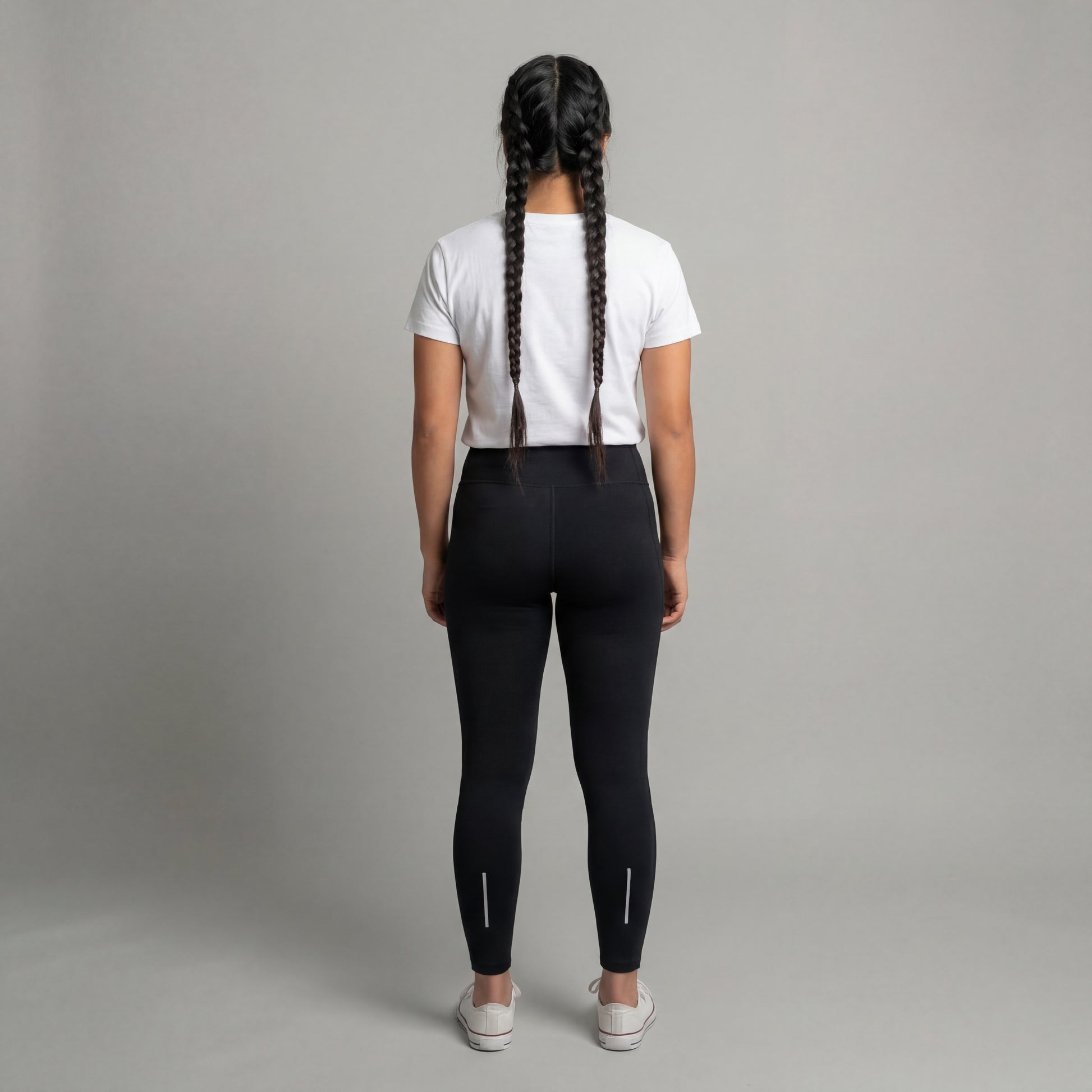 Person wearing black leggings and a white t-shirt on a gray background