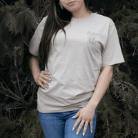 Person wearing Sweetgrass Medicine Tee in beige Indigenous streetwear with cultural design